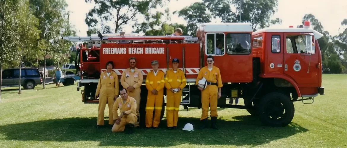 Freemans Reach firefighters in orange in front of an old fire truck