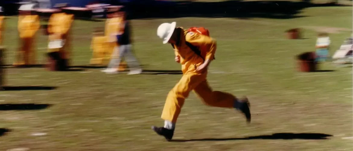 Firefighter in an orange uniform running with a backpack